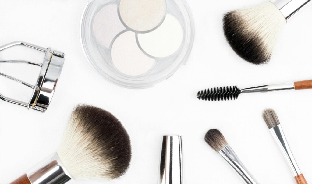 Flat lay of various makeup brushes and tools on a white background.